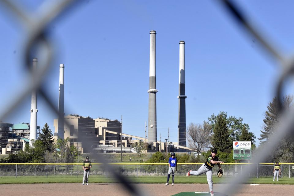 The coal-fired Colstrip Generating Station is seen behind youths playing baseball on Tuesday, May 28, 2024, in Colstrip, Mont. The EPA says the plant is the highest emitter of toxic metal pollutants in the nation. (AP Photo/Matthew Brown)