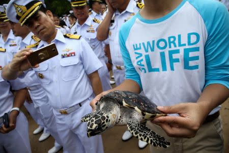 A well-wisher holds a sea turtle at the Sea Turtle Conservation Center as part of the celebrations for the upcoming 65th birthday of Thai King Maha Vajiralongkorn Bodindradebayavarangkun, in Sattahip district, Chonburi province, Thailand, July 26, 2017. REUTERS/Athit Perawongmetha