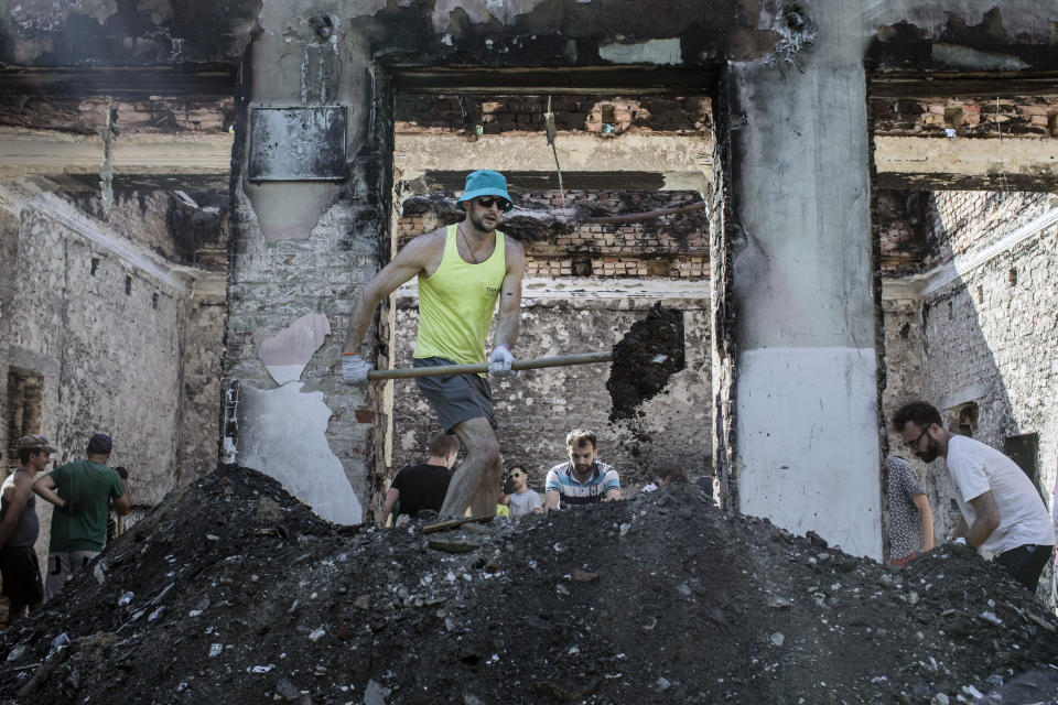 Voluntarios reunidos por el grupo activista Repair Together trabajan para limpiar los escombros de la ruina bombardeada de un edificio dañado por la guerra en Yahidne, Ucrania, el 23 de julio de 2022. (Emile Ducke/The New York Times)