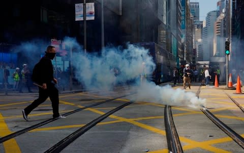 A protester approaches a gas canister deployed in Central district of Hong Kong on Monday - Credit: Vincent Yu/AP