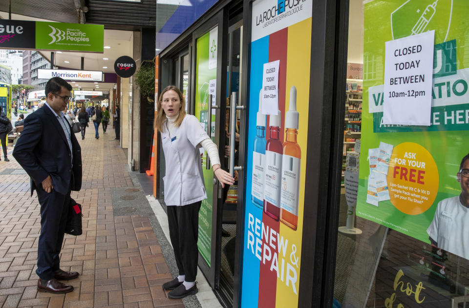 A staff member stands outside a pharmacy that closed for two hours in central Wellington, New Zealand, Wednesday, June, 23, 2021. After enjoying nearly four months without any community transmission of the coronavirus, New Zealanders were on edge Wednesday after health authorities said an infectious traveler from Australia had visited over the weekend. (Mark Mitchell/NZ Herald via AP)