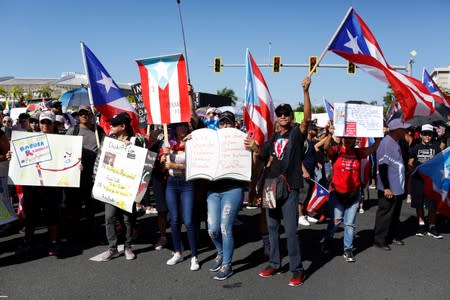 People chant slogans as they wave Puerto Rican flags during ongoing protests calling for the resignation of Governor Ricardo Rossello in San Juan