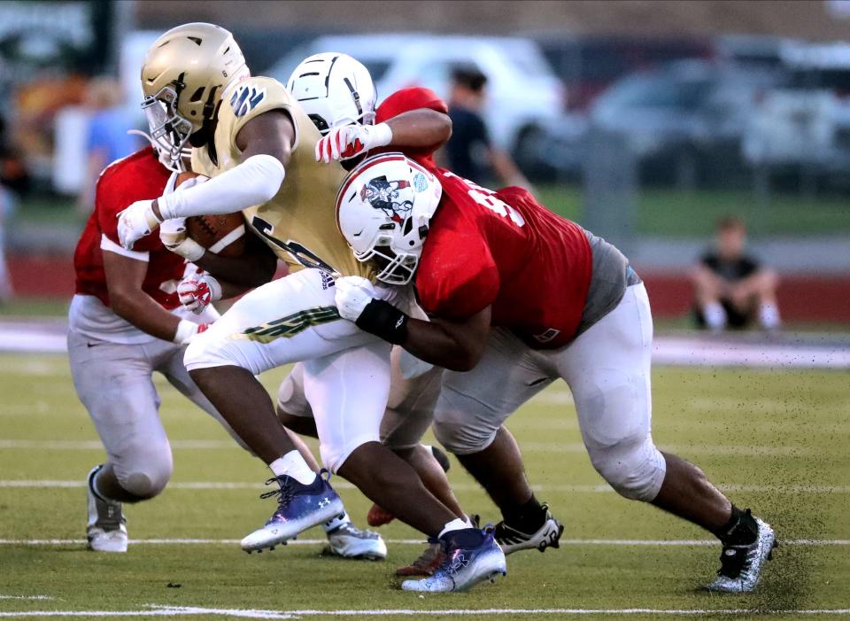 Independence's Tre Hartwell (6) runs the ball as he is taken down by Oakland's Nathan Hepborn (33), Oakland's Cameron Floyd (9) and another Oakland player (94) during a scrimmage on Thursday, Aug. 11, 2022, at Oakland High School.