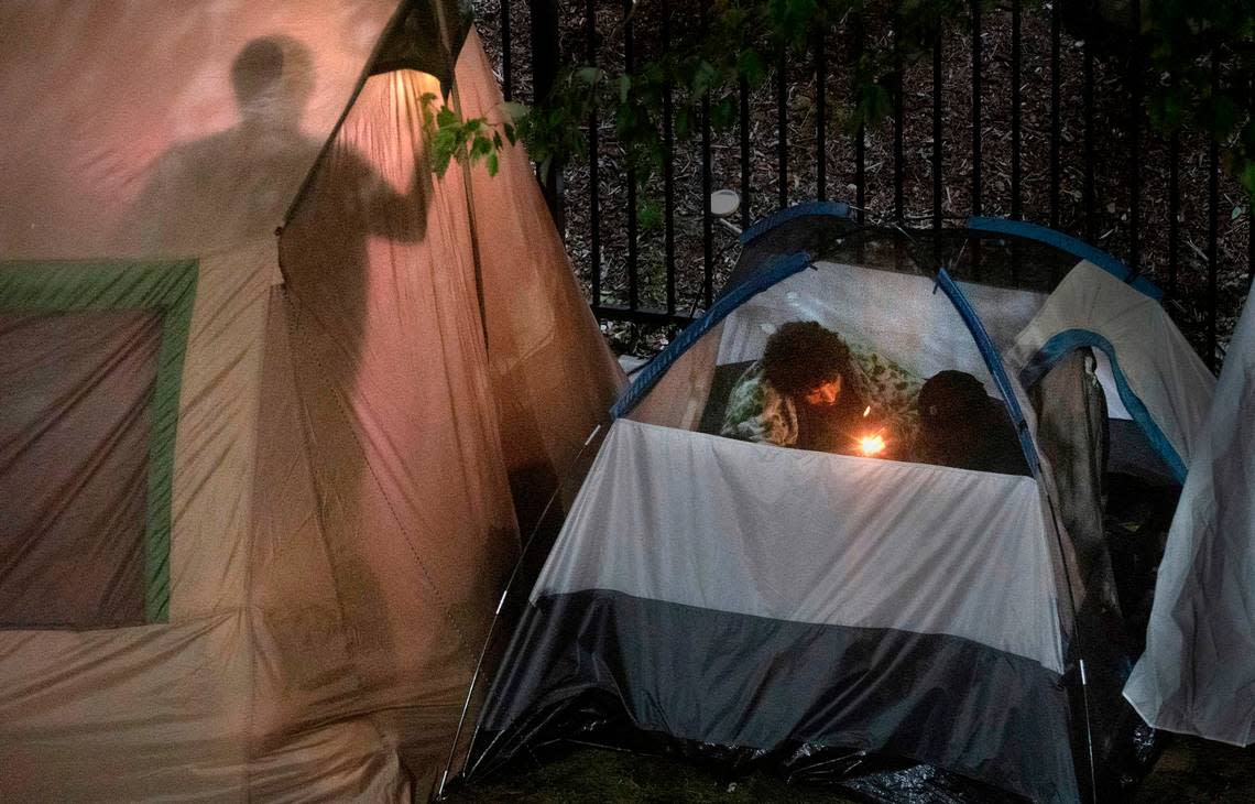 Three men prepare to smoke from a glass pipe at a homeless encampment along 82nd Street between the Best Western Plus and Hampton Inn & Suites on Hosmer Street in Tacoma, Washington on June 28, 2022.