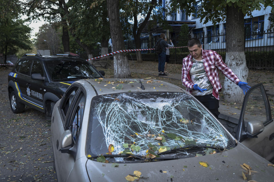 A man inspects his damaged car after a Russian rocket attack in Kyiv, Ukraine, Thursday, Sept. 21, 2023. (AP Photo/Roman Hrytsyna)