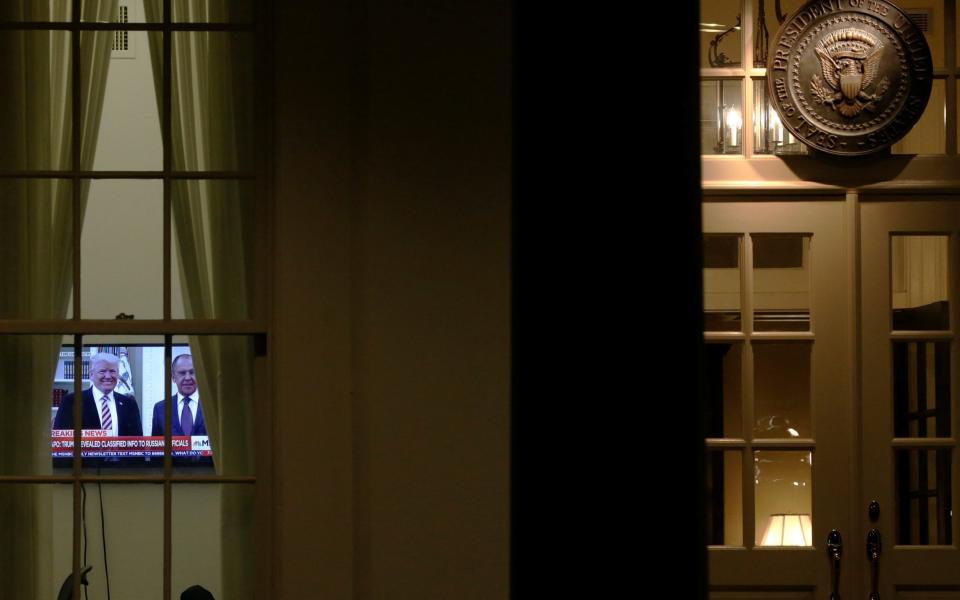 A television airs a report on Donald Trump's recent Oval Office meeting with Sergei Lavrov as night falls on the White House - Credit: Reuters