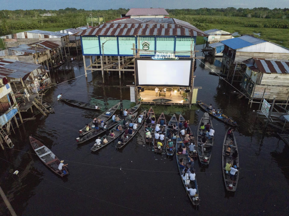 Spectators sit on boats watching a film projected on a screen set up on a wooden structure during the Muyuna Floating Film Festival, that celebrares tropical forests, in the Belen neighborhood of Iquitos, Peru, Saturday, May 25, 2024. (AP Photo/Rodrigo Abd)