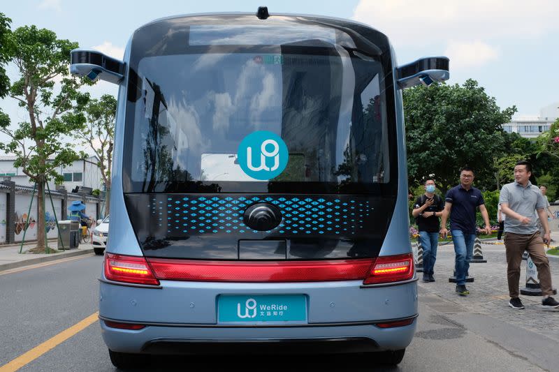 People walk past a WeRide autonomous driving robobus near its office in Guangzhou