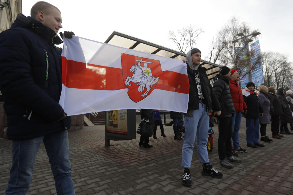 Protesters hold a historical Belarusian flag during a rally in downtown Minsk, Belarus, Saturday, Dec. 7, 2019. Several hundreds demonstrators gathered to protest against closer integration with Russia. (AP Photo/Sergei Grits)