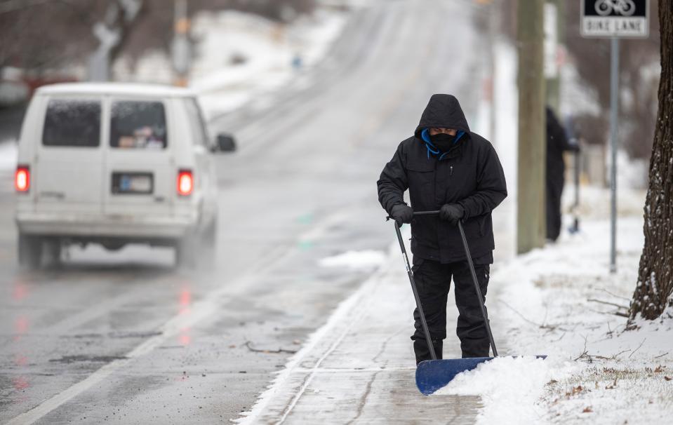 Fausto Lopez uses a wheeled plow to help a crew clear snow from the sidewalk in front of Irvington Community Middle School as about an inch of snow falls on central Indiana, Sunday, Jan. 23, 2022. A little more snow could fall Monday morning. 