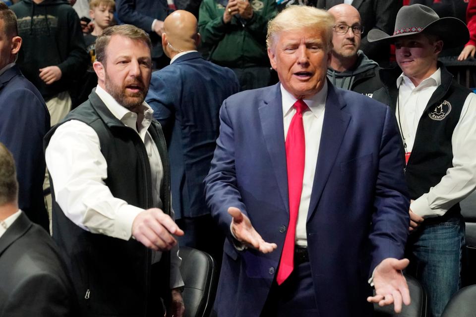 U.S. Sen. Markwayne Mullin, left, and former President Donald J. Trump, right, gesture to fans as they talk before the NCAA Wrestling Championships, Saturday, March 18, 2023, in Tulsa, Okla. (AP Photo/Sue Ogrocki)