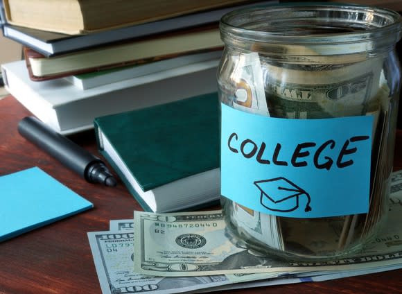 Glass jar with money that says college on top of more money and next to a pile of books