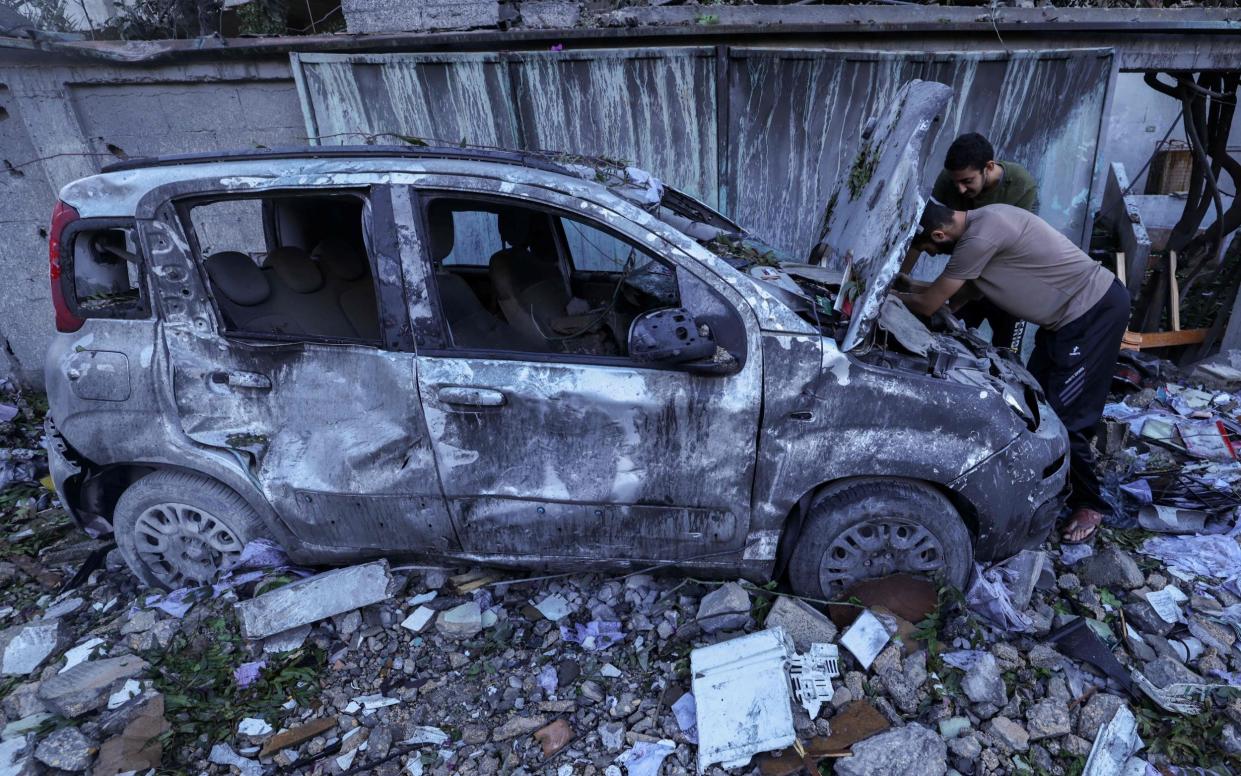 Palestinians inspect their destroyed car after an Israeli airstrike in the Rafah refugee camp in the southern of Gaza Strip, on October 16, 2023