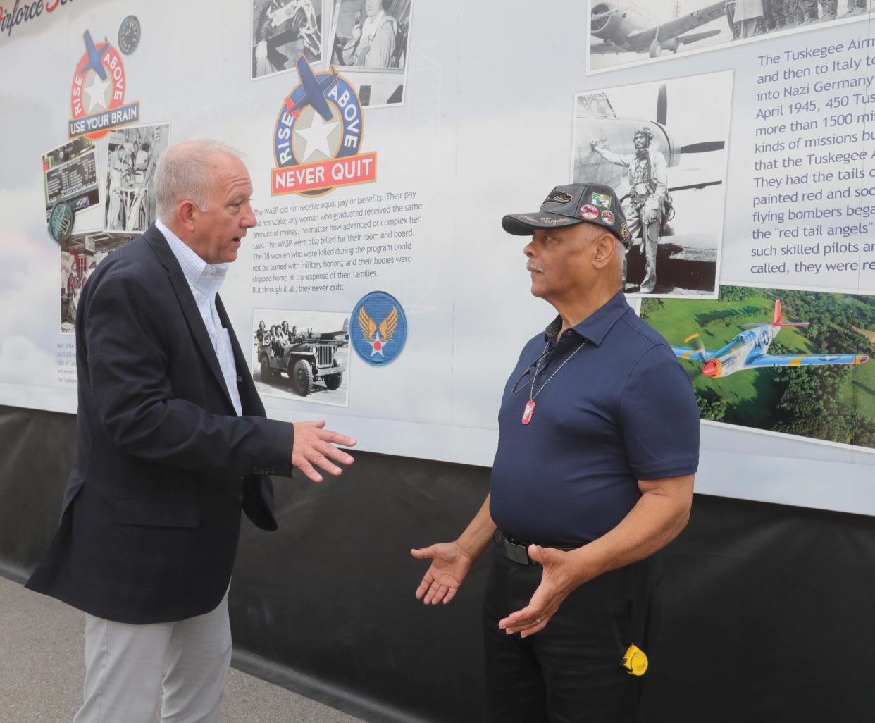 Akron Mayor Dan Horrigan talks with volunteer and Air Force Veteran Bill Wade on Wednesday after viewing The Rise Above Traveling Exhibit featuring Women Air Force Service Pilots and Tuskegee Airmen parked in front of Canal Park.