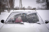 A child waits inside a car as people queue outside for humanitarian aid in the village of Zelene, Ukraine, Saturday, Feb. 18, 2023. The United States has determined that Russia has committed crimes against humanity in Ukraine, Vice President Kamala Harris said Saturday, insisting that "justice must be served" to the perpetrators. (AP Photo/Vadim Ghirda)