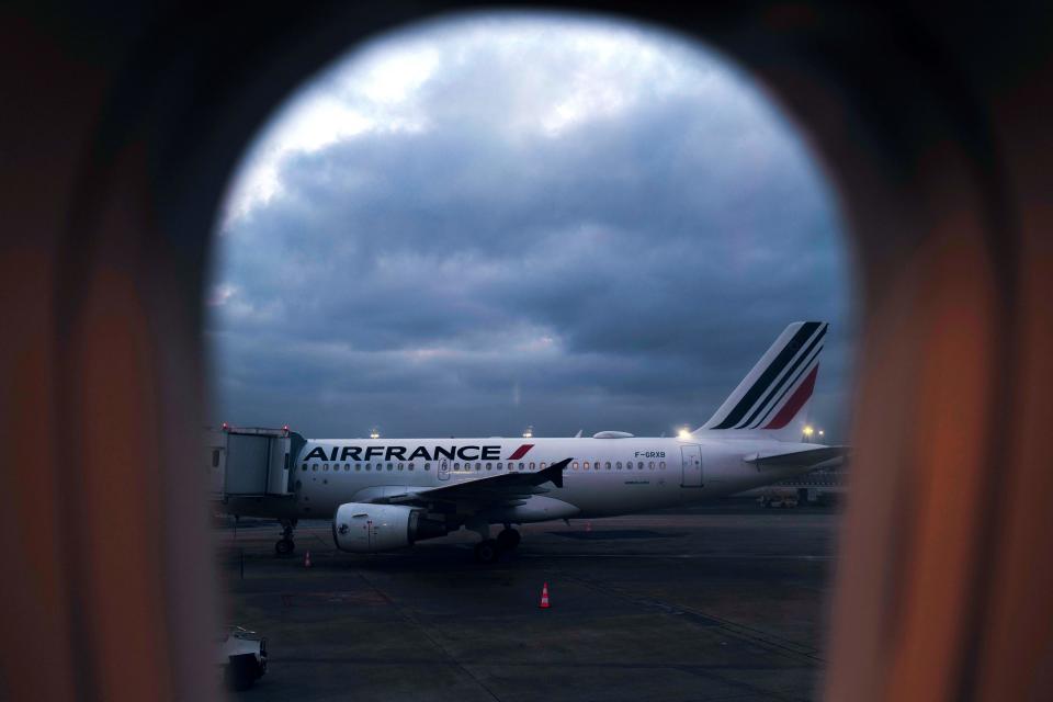 A picture taken through the window of a plane shows an Air France plane parked at an airport.