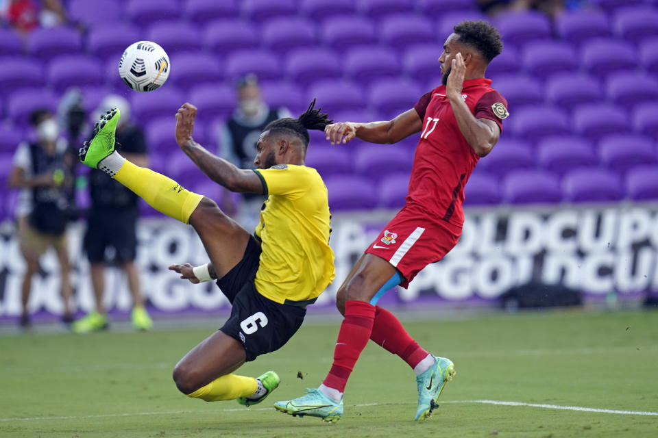El zaguero jamaiquino Liam Moore trata de alcanzar un balón frente a Skeveen Romage, de Guadalupe, en un partido de la Copa de Oro, disputado el viernes 16 de julio de 2021 en Orlando (AP Foto/John Raoux)