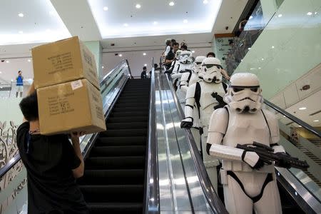 A store staff carries boxes as actors dressed up as Stormtrooper take an escalator before the launch of the film's new toys in Hong Kong, China, September 3, 2015. REUTERS/Tyrone Siu