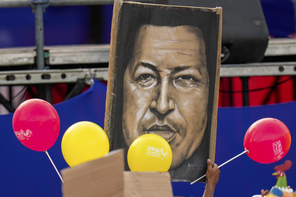 Seguidores del presidente Nicolás Maduro sostienen una imagen del fallecido expresidente Hugo Chávez durante un acto de campaña en Caracas, Venezuela, el jueves 25 de julio de 2024. (AP Foto/Fernando Vergara)