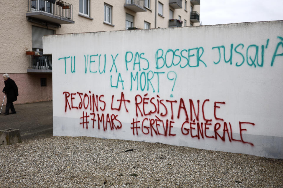 Una mujer mayor pasa junto a una pintada con la frase "¿Quiere trabajar hasta la muerte? Únase a la resistencia #7demarzo #huelgageneral", en Estrasburgo, en el este de Francia, el 5 de marzo de 2023. (AP Foto/Jean-Francois Badias)