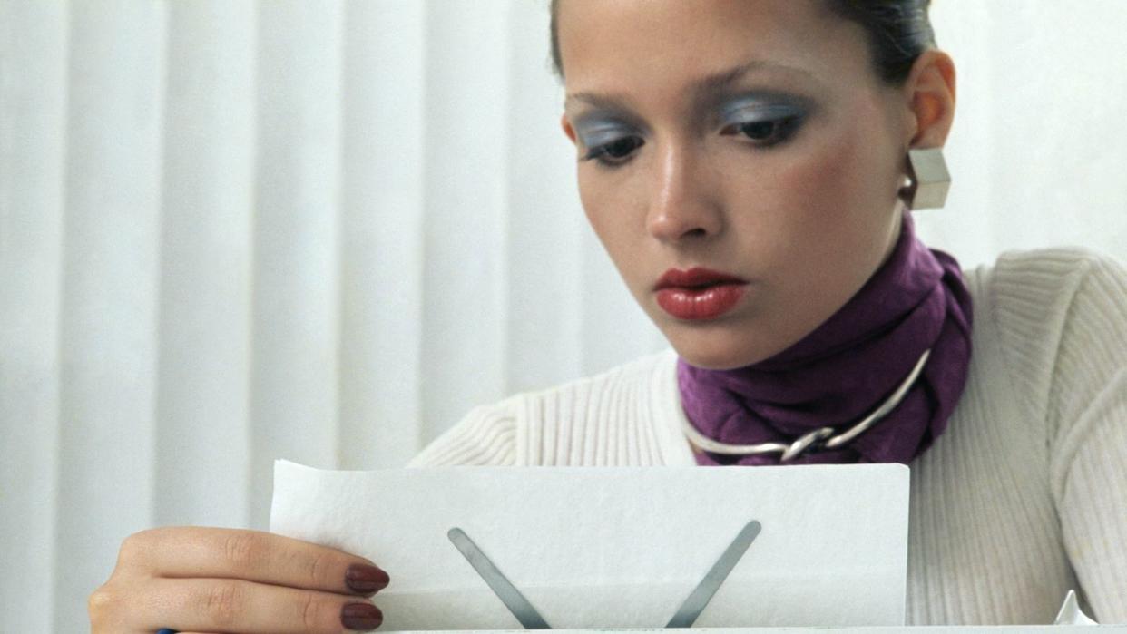 model reading a memo in the workplace, russian sable fingernail polish by revlon, ribbed white shirt from saint laurent rive gauche, earrings by rf clark for william de lillo, scarf by echo, puig doria choker for barcelona designs, hair and makeup by franklyn welsh photo by kourken pakchaniancondé nast via getty images