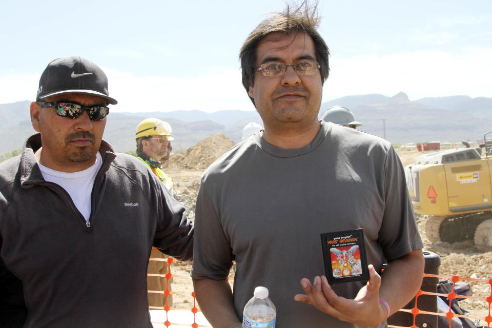 Alamogordo residents Armando Ortega, left, and Raul Ruiz pose for a photograph with a cartridge they found buried in a landfill in Alamogordo, N.M., Saturday, April 26, 2014. Producers of a documentary dug in an southeastern New Mexico landfill in search of millions of cartridges of the Atari 'E.T. the Extra-Terrestrial' game that has been called the worst game in the history of video gaming and were buried there in 1983. (AP Photo/Juan Carlos Llorca)