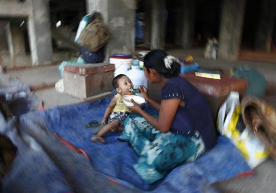 A worker feeds her son at a construction site in Yangon, January 24, 2012.