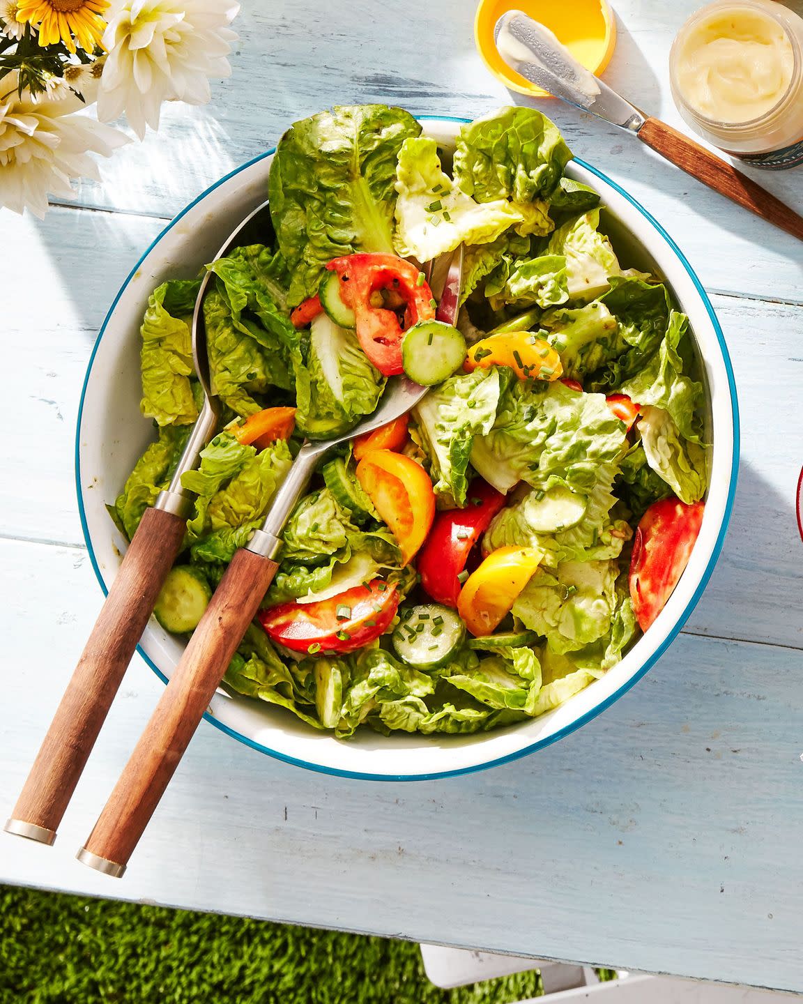 tossed salad with green goddess dressing in a large serving bowl with serving utensils