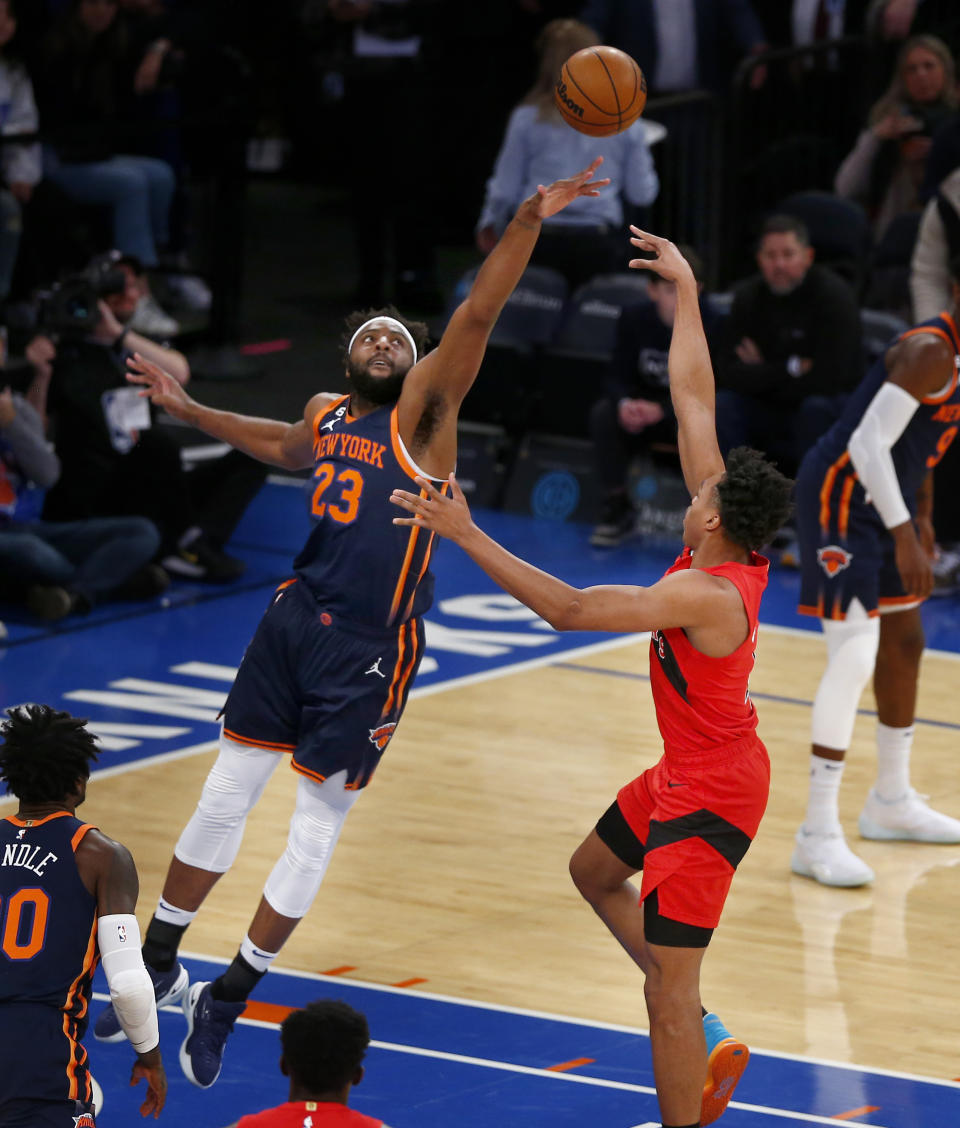 New York Knicks center Mitchell Robinson, left, defends Toronto Raptors guard Scottie Barnes during the first half of an NBA basketball game, Wednesday, Dec. 21, 2022, in New York. (AP Photo/John Munson)