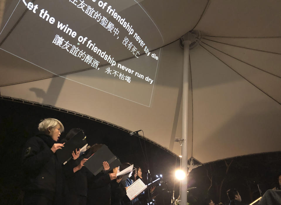 In this Tuesday, Dec. 10, 2019 photo, lyrics are projected on a canopy as a theater troupe performs Les Miserables in at an outdoor event space in Hong Kong. A Hong Kong theater troupe is making audiences weep by touring a stirring production of 'Les Miserables.' Based on Victor Hugo's tale of rebellion in 19th-century France, the rousing music and lyrics of struggle and resistance struck chords with audience members emotionally and physically drained after six months of protests that have convulsed the city. (AP Photo/John Leicester)