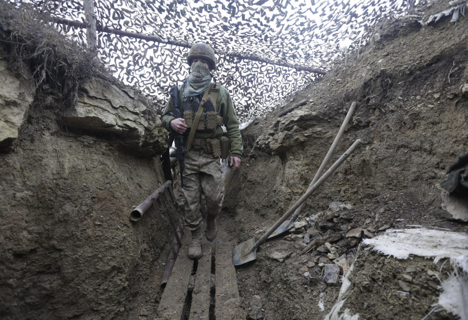 Ukrainian soldiers walks under a camouflage net in a trench on the line of separation from pro-Russian rebels near Debaltsevo, Donetsk region, Ukraine, Ukraine Friday, Dec 3, 2021. In this Friday, the Ukrainian defense minister warned that Russia could invade his country next month. Russia-West tensions escalated recently with Ukraine and its Western backers becoming increasingly concerned that a Russian troop buildup near the Ukrainian border could signal Moscow's intention to invade. (AP Photo/Andriy Dubchak)