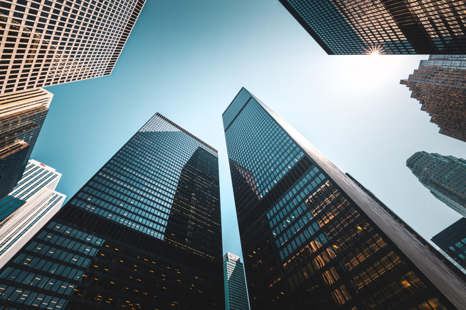 Skyscrapers from a low angle view with clear skies and the sun peeking through