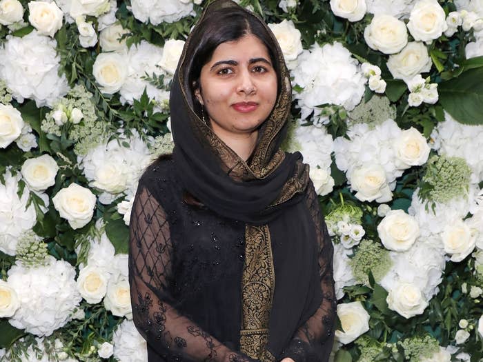 Malala poses in front of a wall of flowers