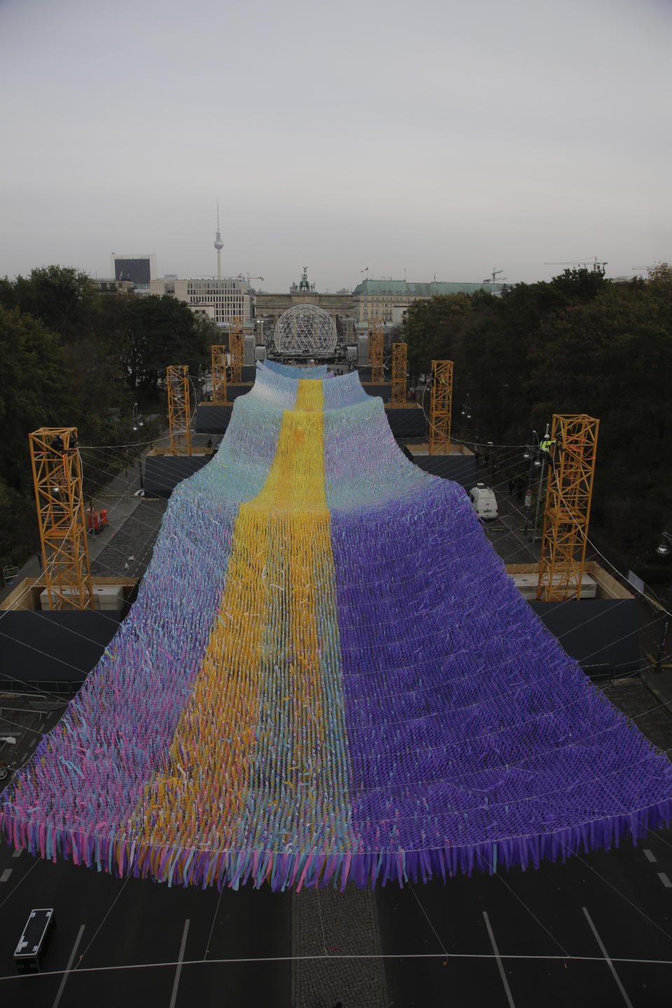 The skynet artwork 'Visions In Motion' overhangs the 'Strasse des 17. Juni' (Street of June 17) boulevard in front of the Brandenburg Gate in Berlin, Germany, Friday, Nov. 1, 2019. The art work by Patrick Shearn was made with about 100.000 streamers with written messages and is part of the celebrations marking the 30th anniversary of the fall of the Berlin Wall on Nov 9, 2019. (AP Photo/Markus Schreiber)