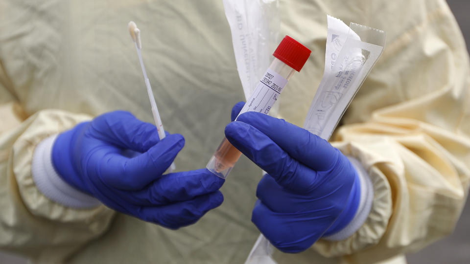 A nurse holds swabs and test tube to test people for COVID-19