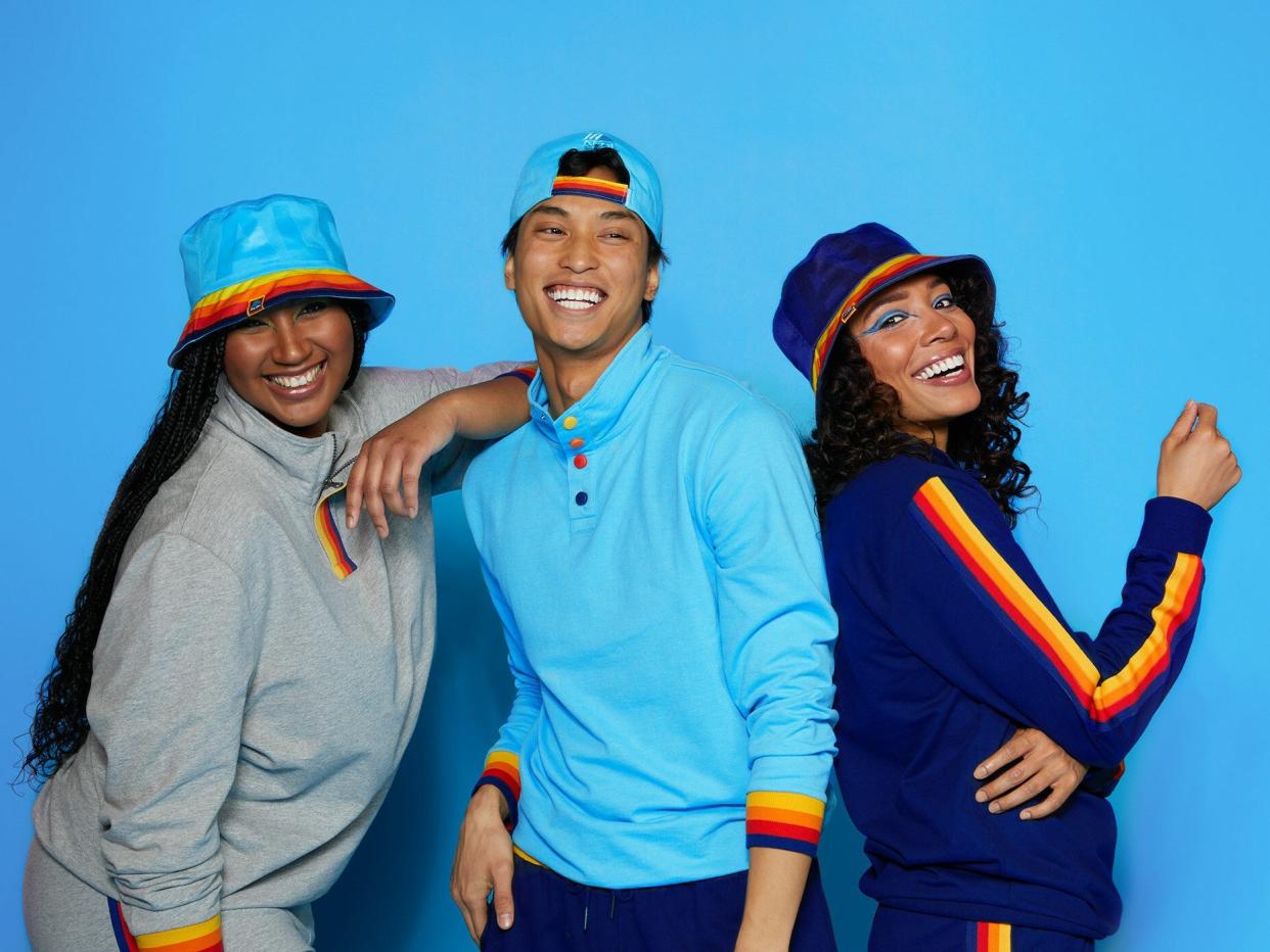 Three people wear Aldi-branded hats, jackets, and pants, featuring blue, red, orange, and yellow stripes and the Aldi logo.