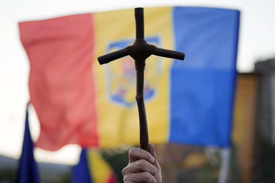 A man holds a wooden cross during an anti-government and anti-vaccination protest organised by the far-right Alliance for the Unity of Romanians or AUR, in Bucharest, Romania, Saturday, Oct. 2, 2021. Thousands took to the streets calling for the governments resignation, as Romania reported 12.590 new COVID-19 infections in the past 24 hour interval, the highest ever daily number since the start of the pandemic. (AP Photo/Vadim Ghirda)