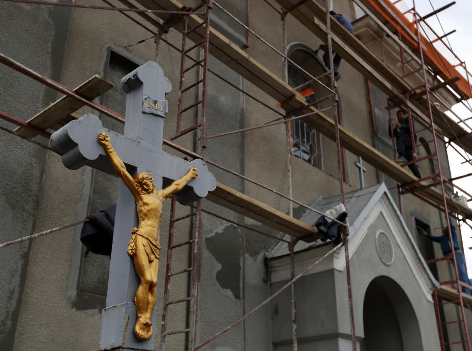 In this Thursday, Oct. 18, 2018 photograph, a man works on scaffolding outside a Catholic Church in Chop, Ukraine. A new education law that could practically eliminate the use of Hungarian and other minority languages in schools after the 4th grade is just one of several issues threatening this community of 120,000 people. Many are worried that even as Ukraine strives to bring its laws and practices closer to European Union standards, its policies for minorities seem to be heading in a far more restrictive direction. (AP Photo/Laszlo Balogh)