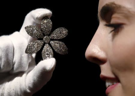 An employee holds a George III diamond flower brooch, part of the collection of former British prime minister Margaret Thatcher during an auction preview at Christie's in London, Britain, December 11, 2015. REUTERS/Peter Nicholls