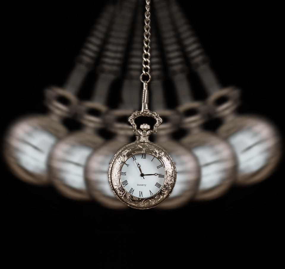 Pocket watch silver swinging on a chain black background to hypnotize