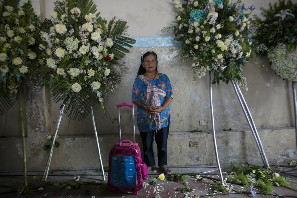 A supporter of Peru's late President Alan Garcia's stands among funeral flowers inside the political party headquarters where his wake is taking place in Lima, Peru, Friday, April 19, 2019. Garcia shot himself in the head and died Wednesday as officers waited to arrest him in a massive graft probe that has put the country's most prominent politicians behind bars and provoked a reckoning over corruption. (AP Photo/Rodrigo Abd)