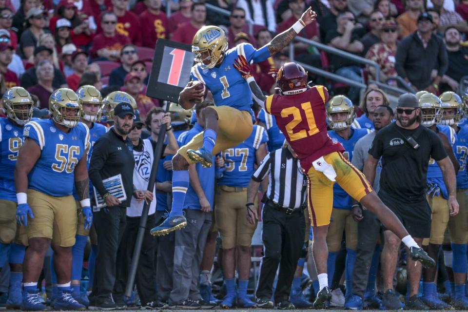 UCLA quarterback Dorian Thompson-Robinson is shoved out of bounds by USC cornerback Olaijah Griffin
