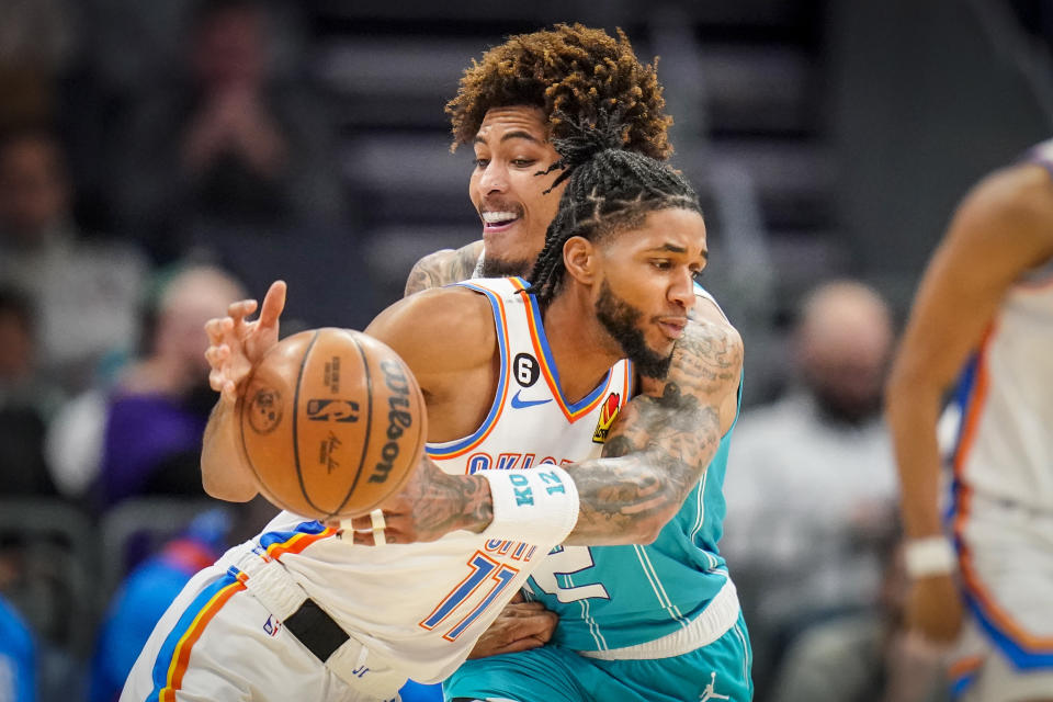 Charlotte Hornets guard Kelly Oubre Jr., rear, reaches for the ball around Oklahoma City Thunder guard Isaiah Joe, front, during the first half of an NBA basketball game Thursday, Dec. 29, 2022, in Charlotte, N.C. (AP Photo/Rusty Jones)