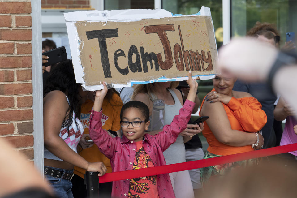 Paul Nabinett, de 9 años, sostiene un cartel en apoyo de Johnny Depp mietras seguidores del actor reaccionan al veredicto en la demanda por difamación de Depp contra su exesposa Amber Heard, frente al juzgado del condado de Fairfax en Fairfax, Virginia, el miércoles 1 de junio de 2022. (Foto AP/Craig Hudson)