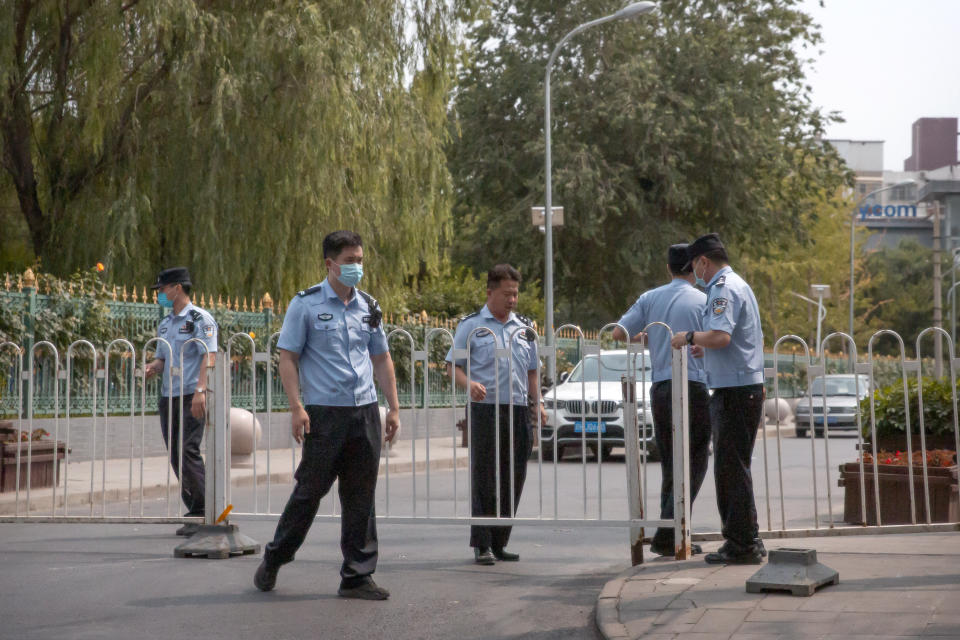 Police officers pull a barricade across a road leading to the a residential neighborhood near the Xinfadi wholesale food market district in Beijing, Saturday, June 13, 2020. Beijing closed the city's largest wholesale food market Saturday after the discovery of seven cases of the new coronavirus in the previous two days. (AP Photo/Mark Schiefelbein)