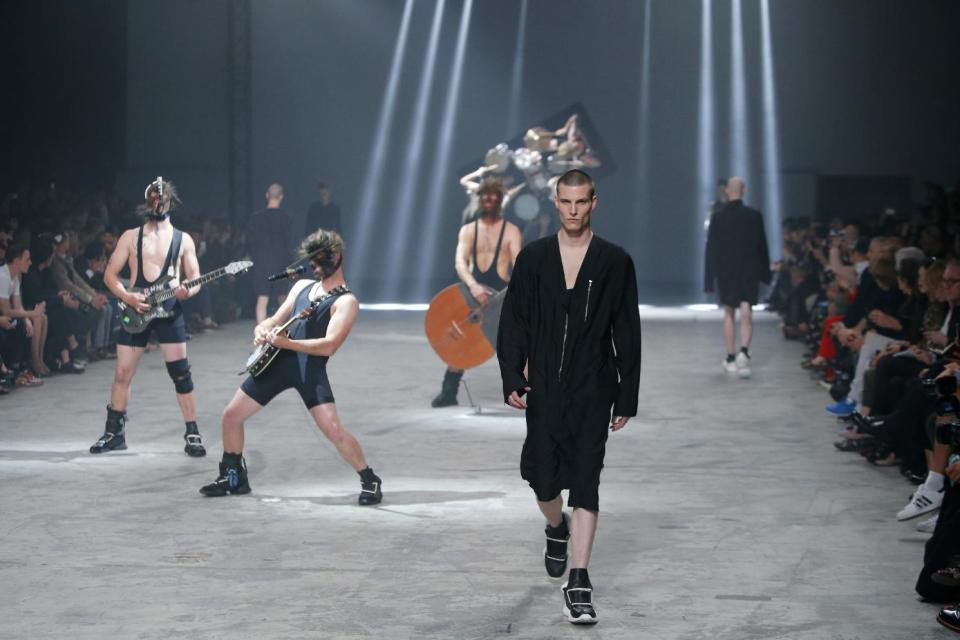 A model wears a creation by fashion designer Rick Owens as part of his men's fashion Spring-Summer 2014 collection, presented Thursday, June 27, 2013 in Paris, as Estonian metal/punk band Winny Puhh performs live, rear . (AP Photo/Francois Mori)