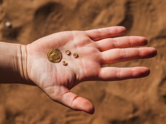 Inside of an ancient garbage pit, archaeologists discovered precious artifacts, including a gold coin and three items inlaid with gold that adorned jewelry.