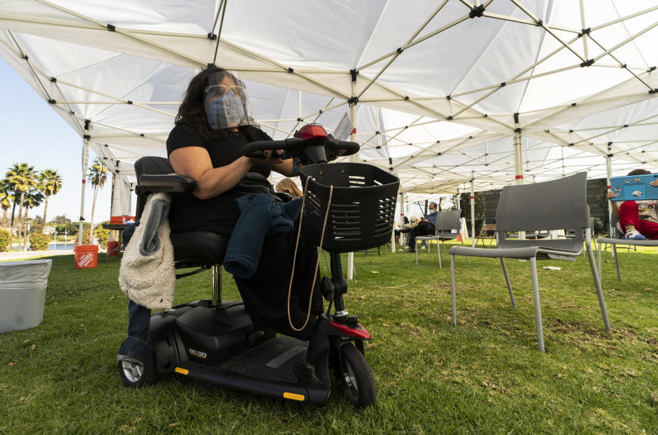 Veronica Lopez, 42, who has Spina bifida, wears a face shield and mask as she waits at the recovery tent for 15 minutes after being vaccinated at the St. John's Well Child and Family Center's COVID-19 vaccination site at the East Los Angeles Civic Center in Los Angeles, Thursday, March 4, 2021. California will begin setting aside 40% of all vaccine doses for the state's most vulnerable neighborhoods in an effort to inoculate people most at risk from the coronavirus more quickly. (AP Photo/Damian Dovarganes)