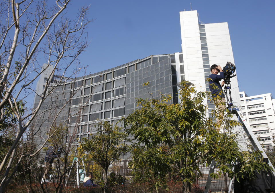 A cameraman on a ladder stands by outside Tokyo Detention Center, where former Nissan chairman Carlos Ghosn and former another executive Greg Kelly are being detained, in Tokyo Friday, Dec. 21, 2018. Japanese media say prosecutors have added a new allegation of breach of trust against Ghosn, dashing his hopes for release on bail.(AP Photo/Shuji Kajiyama)