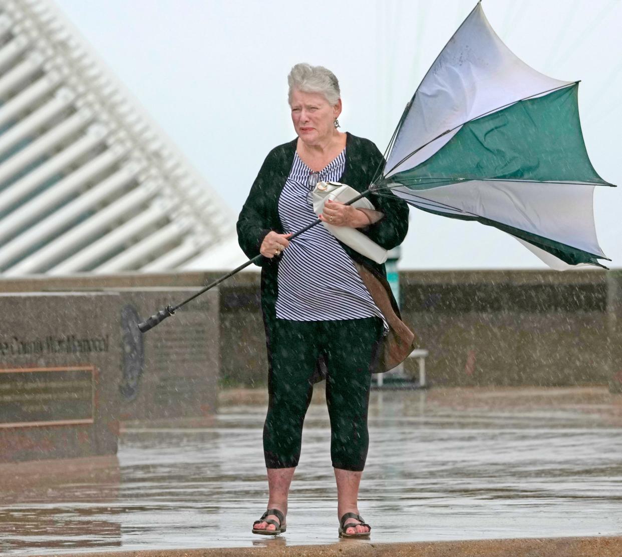 A woman, Pat, who only wanted to use her first name, from Florida,  fights to keep her umbrella open in the wind and rain while waiting for her ride to pick her up in front of the Milwaukee County War Memorial Center on North Lincoln Memorial Drive in Milwaukee on Sunday, Sept. 11, 2022. Rain fell for most of the day Sunday with more expected Monday.